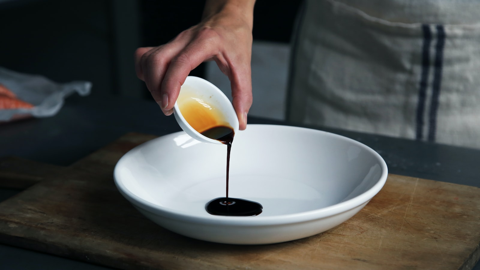 person dripping black liquid from small white ceramic bowl to big white ceramic bowl